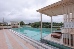 Una piscina con zona techada, una silla de salvavidas y un cartel con las normas de la piscina.