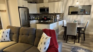 A modern kitchen with white cabinets, stainless steel appliances, and a tiled backsplash.