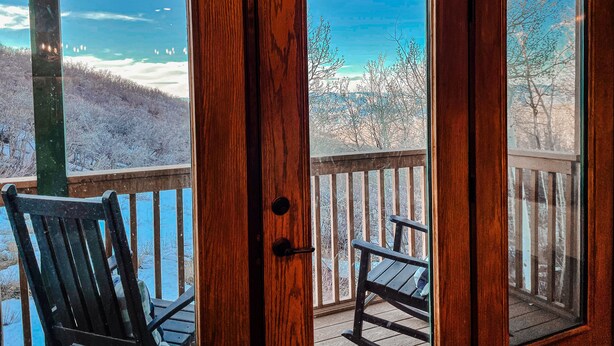 A wooden door with glass panels, a bench, and a view of a snowy landscape.