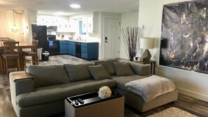 Ein modernes Wohnzimmer mit einem Ecksofa, einem Couchtisch und einem Stadtbild an der Wand.