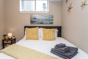 A neatly made bed with two pillows, a bedside lamp, and a folded towel on the right side. - ★Bright Modern Suite ★ Netflix - WiFi ✔Long Stays ★ Clean (Edmonton)