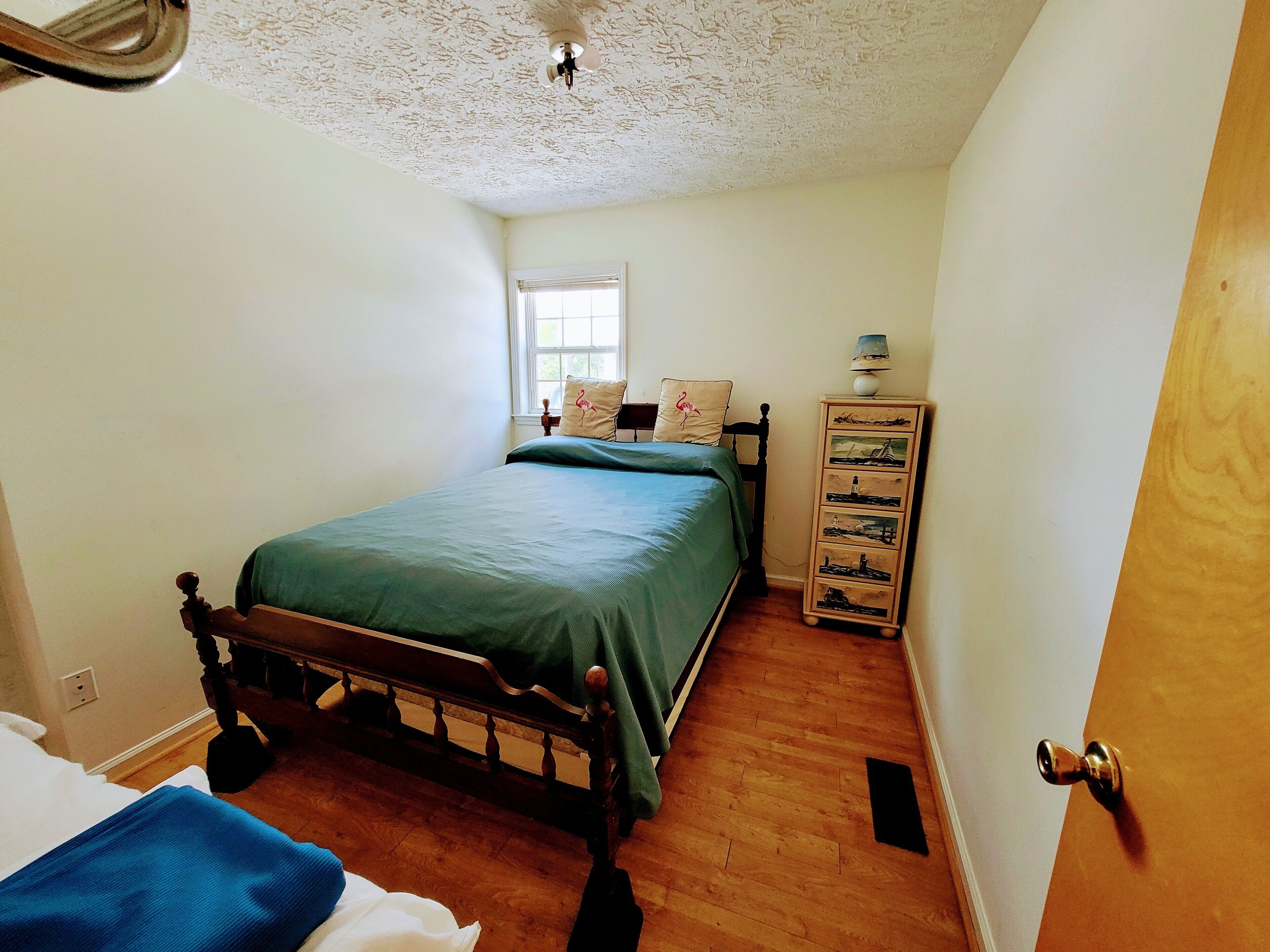 A bedroom with a bed, a dresser, a window, and a ceiling fan.