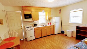 A compact kitchen with basic appliances, a dining area with a table and chairs, and a small sofa. - Sunsplash, Walk to the beach, walk to Main Street (North Myrtle Beach)