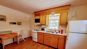 A compact kitchen with wooden cabinets, a stove, a sink, and a refrigerator. - Sunsplash, Walk to the beach, walk to Main Street (North Myrtle Beach)