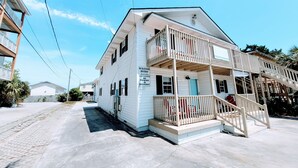 A two-story white house with a balcony, a porch, and a staircase leading to the upper floor. There are signs indicating no parking in the driveway. - Sunsplash, Walk to the beach, walk to Main Street (North Myrtle Beach)