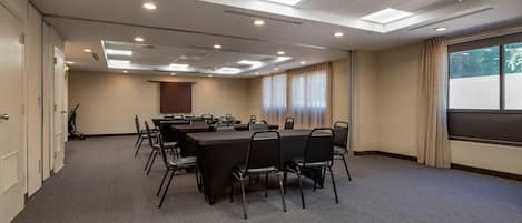 A conference room with a long table, chairs, and a projector screen.