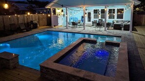 Un giardino con piscina, mobili da esterno e luci decorative.