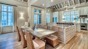 Una cocina amplia con una isla grande, muebles blancos y techo de madera.