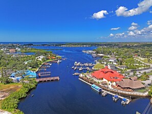 A marina with boats docked, a large building with a red roof, and surrounding greenery.