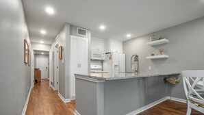 Una cocina con armarios blancos, encimera de granito y una silla blanca.