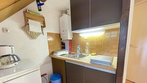 Una cocina compacta con un lavabo, una cafetera y un cubo de basura.