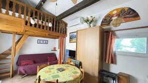Una habitación acogedora con una cama nido de madera, un sofá, una mesa de comedor y un televisor.