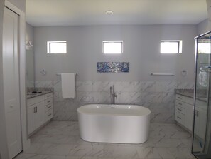 Een bad/douchecombinatie, een bubbelbad, een haardroger, handdoeken