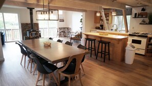 Een moderne keuken met een groot kookeiland, houten vloeren en zwarte barkrukken.