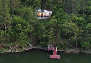 Ein Haus, umgeben von dichtem Wald, verbunden mit einem Steg über dem Wasser.