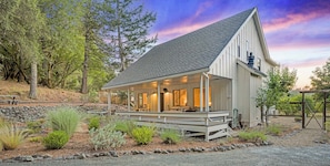 A white building with a sloped roof, a covered porch, and a stone pathway leading to it. - Calistoga Cottage - Hot Tub and Tastings Included (Calistoga)