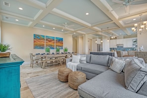 A spacious living room with a sectional sofa, a dining area, and a kitchen in the background. - New Ocean View Beach House with a Heated Private Pool! Park Here Walk Everywhere (Cocoa Beach)