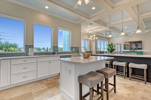 A spacious kitchen with large windows, a central island, and bar stools. - New Ocean View Beach House with a Heated Private Pool! Park Here Walk Everywhere (Cocoa Beach)