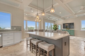 A spacious kitchen with a large island, bar stools, and pendant lighting. - New Ocean View Beach House with a Heated Private Pool! Park Here Walk Everywhere (Cocoa Beach)