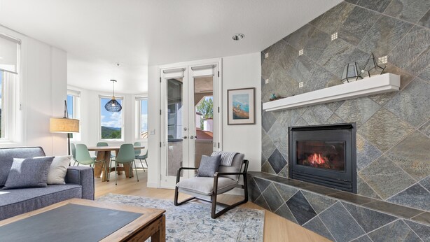 Una sala de estar moderna con chimenea, un comedor con sillas y vistas al exterior.