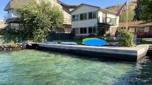 Een helder zwembad met een betonnen terras en een kleine brug. Er staan verschillende kajaks en een paddleboard op het terras.