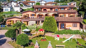 A residential area with multiple houses, a playground, and a paved path. - Lovely apartment for 4 people with pool, WIFI, A/C, TV and terrace (Luino)