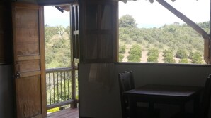 Ein Zimmer mit Holztür, einem Tisch mit Stühlen und Blick auf eine üppige Landschaft durch ein Fenster.