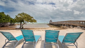 A beach with turquoise chairs and a wooden pier extending into the water.