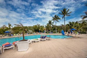 A pool area with lounge chairs and umbrellas, surrounded by palm trees. - Tavernier Oceanfront Resort Condo-Pool, Dockage, Kayaks, Onsite Restaurant & Bar (Tavernier)
