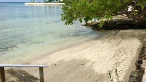 A beach with clear water, a sandy shore, and a small island with palm trees in the distance. - Situated on the Ocean Jacaranda Bay Villa  (Nassau)