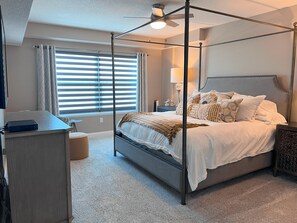 Relax in this serene bedroom with a four-poster bed, desk, and comfortable seating area.