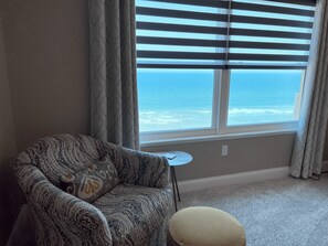 Enjoy the ocean view from the comfort of this room, featuring a cozy armchair and ottoman.