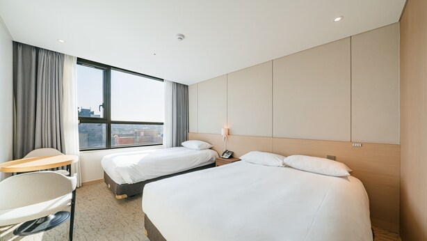 A hotel room with two beds, a desk, and a chair. - Hotel ZINC (Seogwipo)