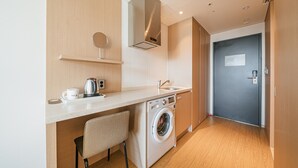A compact kitchen with a washing machine, a coffee maker, and a sink. - Hotel ZINC (Seogwipo)