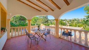 A covered outdoor patio with a table and chairs, a grill, and a view of a lush landscape. - 0306 Villa Monte Verde Granada (Javea / Xàbia)