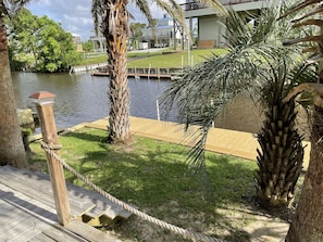 Guests can enjoy serene waterfront views from the deck leading to a lush garden with a palm tree.