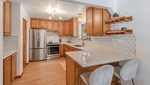 Une cuisine moderne avec des meubles en bois, des appareils électroménagers en acier inoxydable et un plan de travail en marbre.