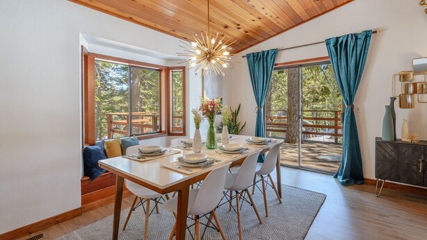 Un espace repas doté d’un plafond en bois, de grandes fenêtres et offrant une vue sur l’extérieur.