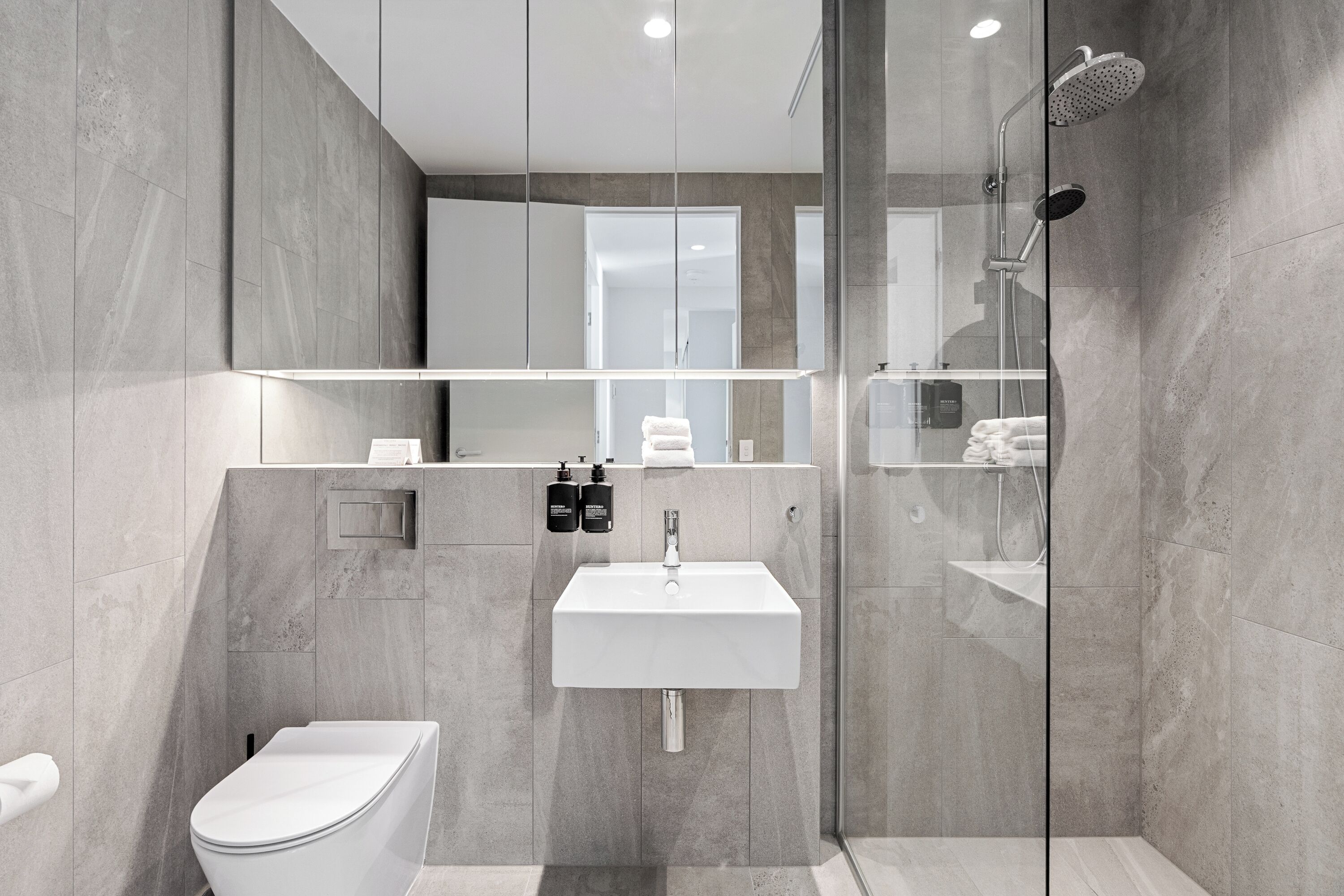 A modern bathroom with a toilet, sink, and shower.
