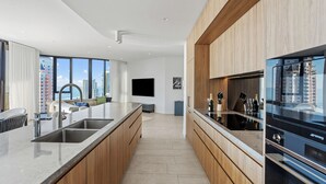 Eine moderne Küche mit einer großen Kochinsel, Edelstahlgeräten und Blick auf die Stadt.