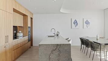 Una cocina moderna con armarios de madera, una isla de mármol y un comedor con sillas.