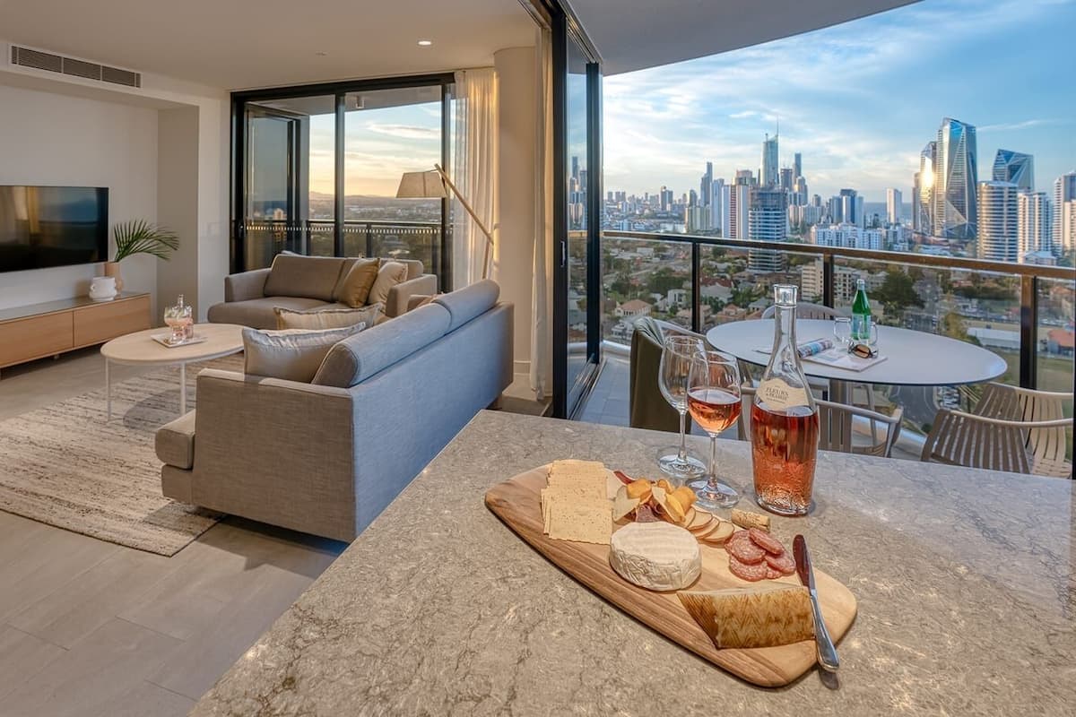 A modern living room with a sofa, a coffee table, and a balcony with a city view.