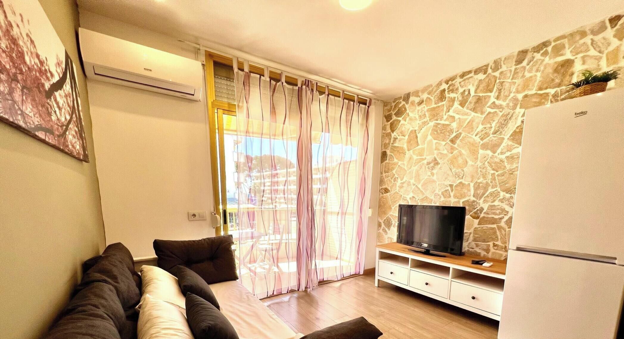 A living room with a sofa, TV, and a stone wall.
