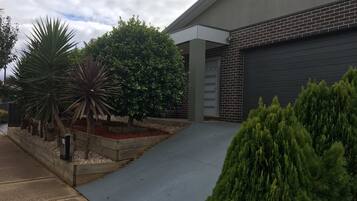 A modern building with a garage door, a concrete driveway, and landscaped areas with various plants.
