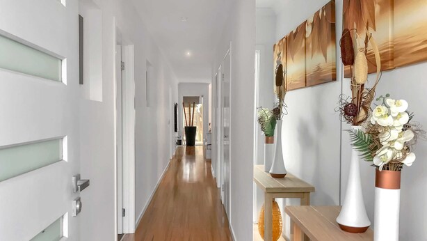 A hallway with wooden flooring, white walls, and a wooden bench with vases. - Sleek Stylish Modern Close to Airport (Fraser Rise)