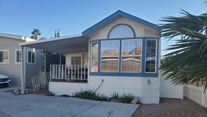 Einbungalow mit überdachter Veranda, Garage und kleinem Vorgarten mit Kies und Steinen.