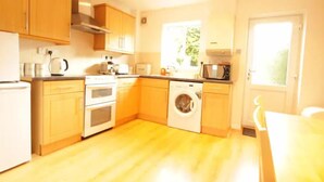 A compact kitchen with wooden cabinets, a built-in oven, a washing machine, and a microwave. - Fantastic 2-Bed House in Hull. Garden, Sky tv. (Hull)