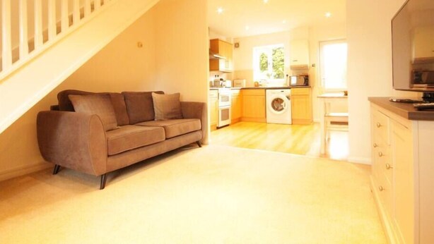 A modern apartment with a living area featuring a sofa, a kitchen with a washing machine, and a staircase. - Fantastic 2-Bed House in Hull. Garden, Sky tv. (Hull)