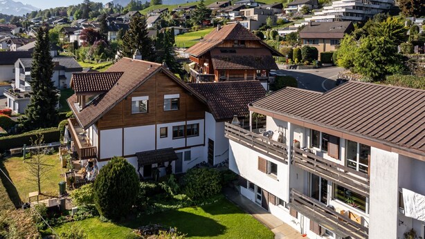 Zona residencial com casas, uma montanha ao fundo e céu claro.