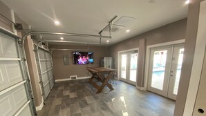 Een ruime garage met meerdere deuren, een houten tafel en een plafondventilator.
